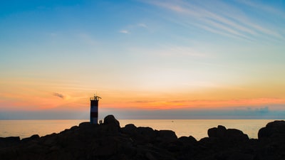 剪影摄影的海边的灯塔在金色的小时
